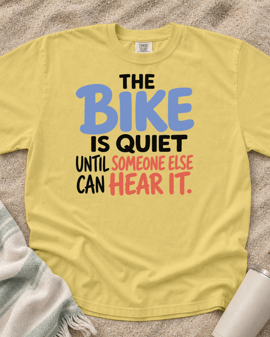 Butter Comfort Colors 1717 tee with The Bike Is Quiet Until Someone Else Can Hear It graphic.