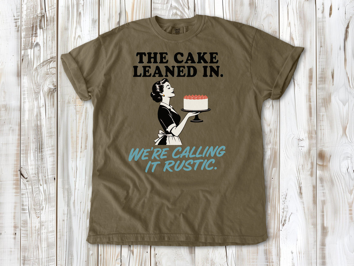 Graphite garment-dyed tee with The Cake Leaned In We're Calling It Rustic baking graphic.