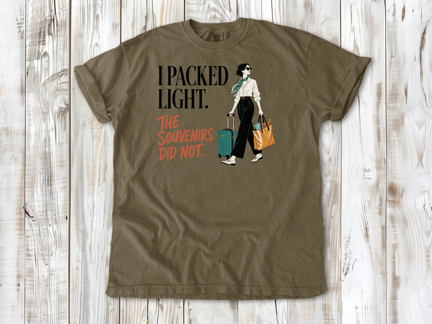 Graphite garment-dyed tee with I Packed Light The Souvenirs Did Not travel graphic.