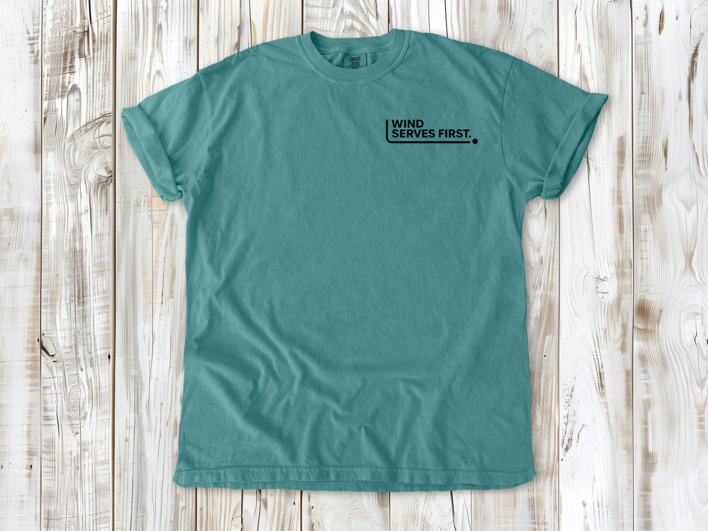 Seafoam garment-dyed tee with Wind Serves First small left-chest beach volleyball graphic.
