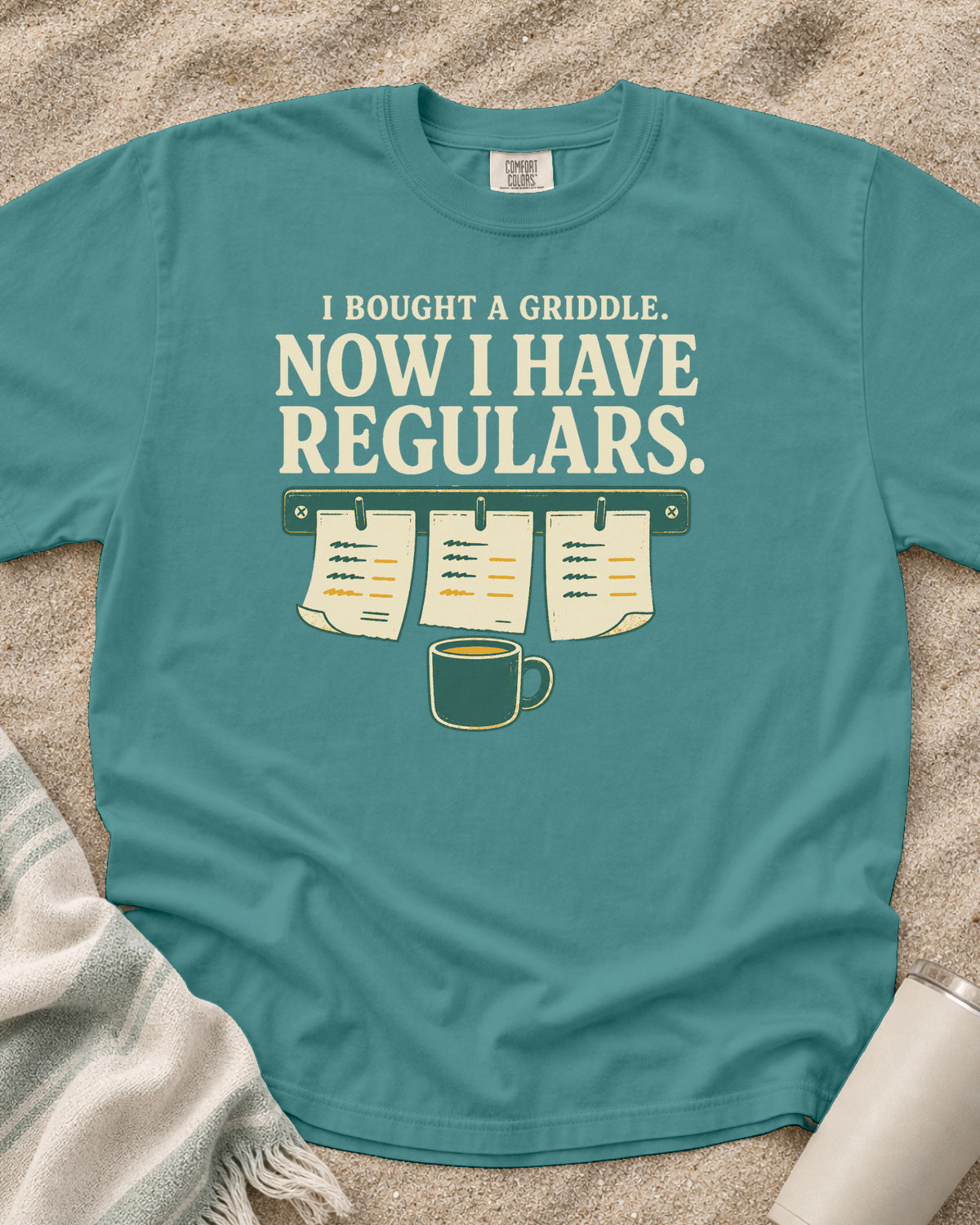 Seafoam garment-dyed tee with I Bought a Griddle Now I Have Regulars graphic.
