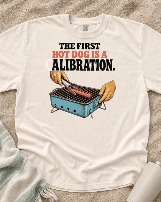 Ivory Comfort Colors 1717 tee with The First Hot Dog Is a Calibration graphic.