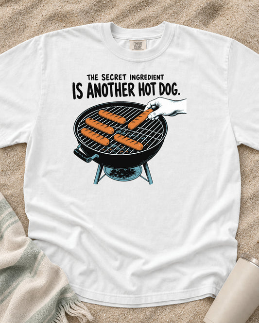 White Comfort Colors 1717 tee with The Secret Ingredient Is Another Hot Dog graphic.