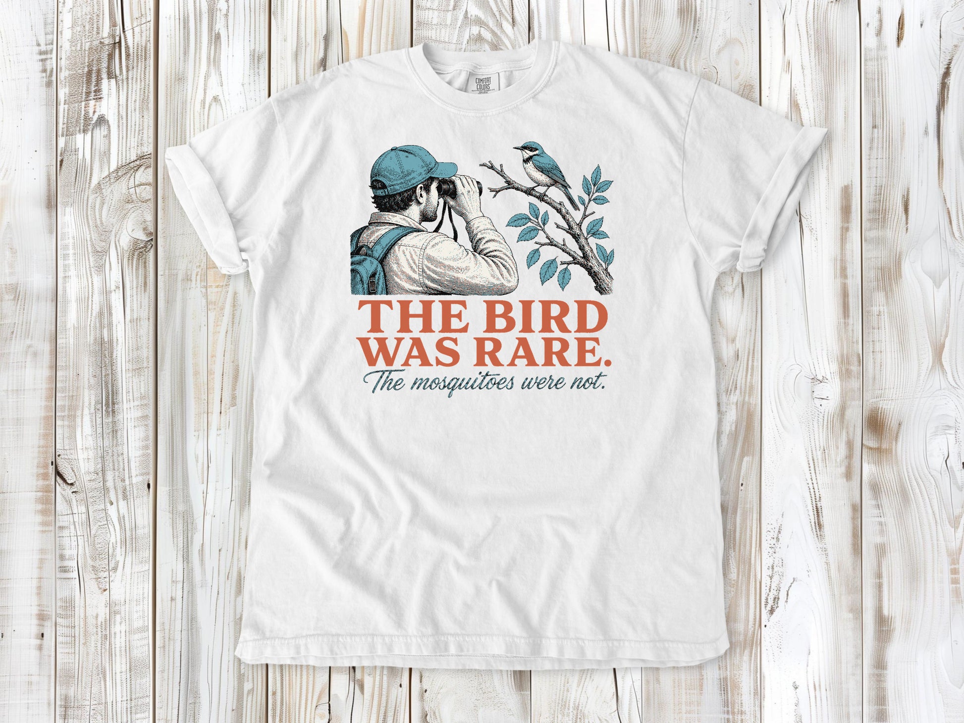 White garment-dyed tee with The Bird Was Rare The Mosquitoes Were Not birdwatching graphic.