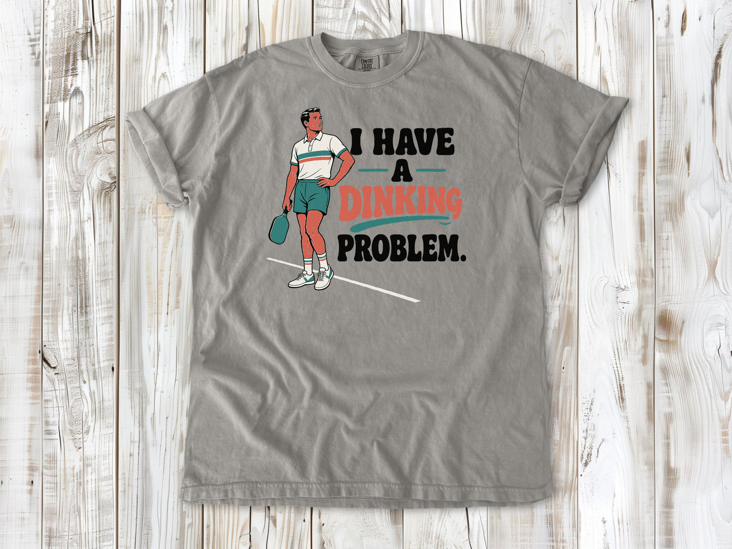 Khaki garment-dyed tee with I Have a Dinking Problem pickleball graphic.