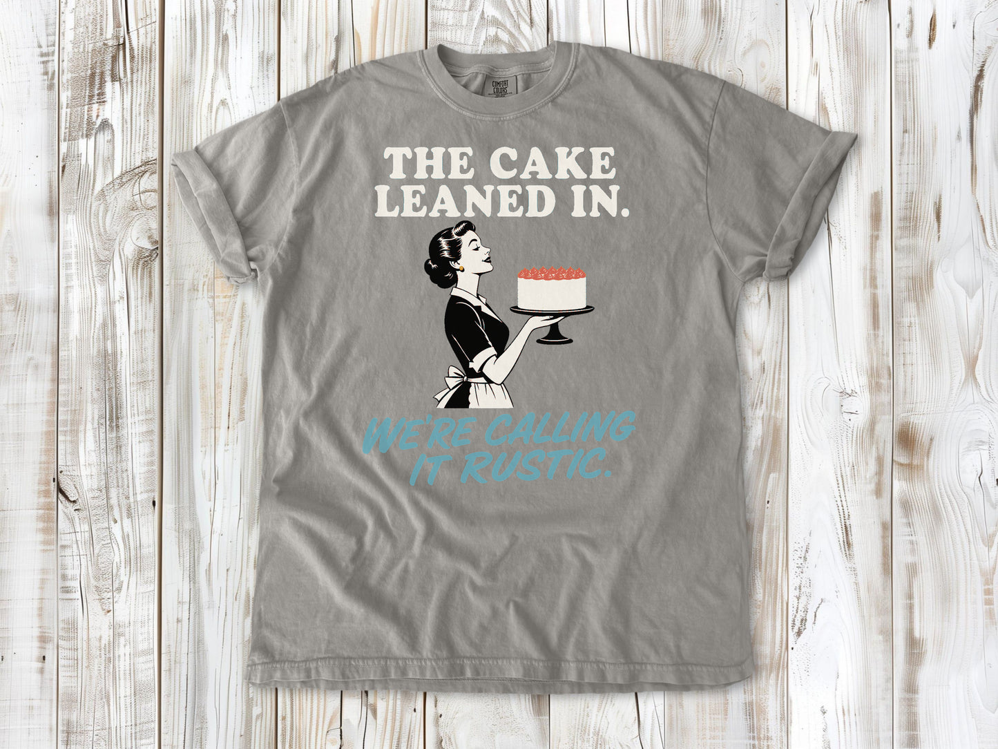 Khaki garment-dyed tee with The Cake Leaned In We're Calling It Rustic baking graphic.