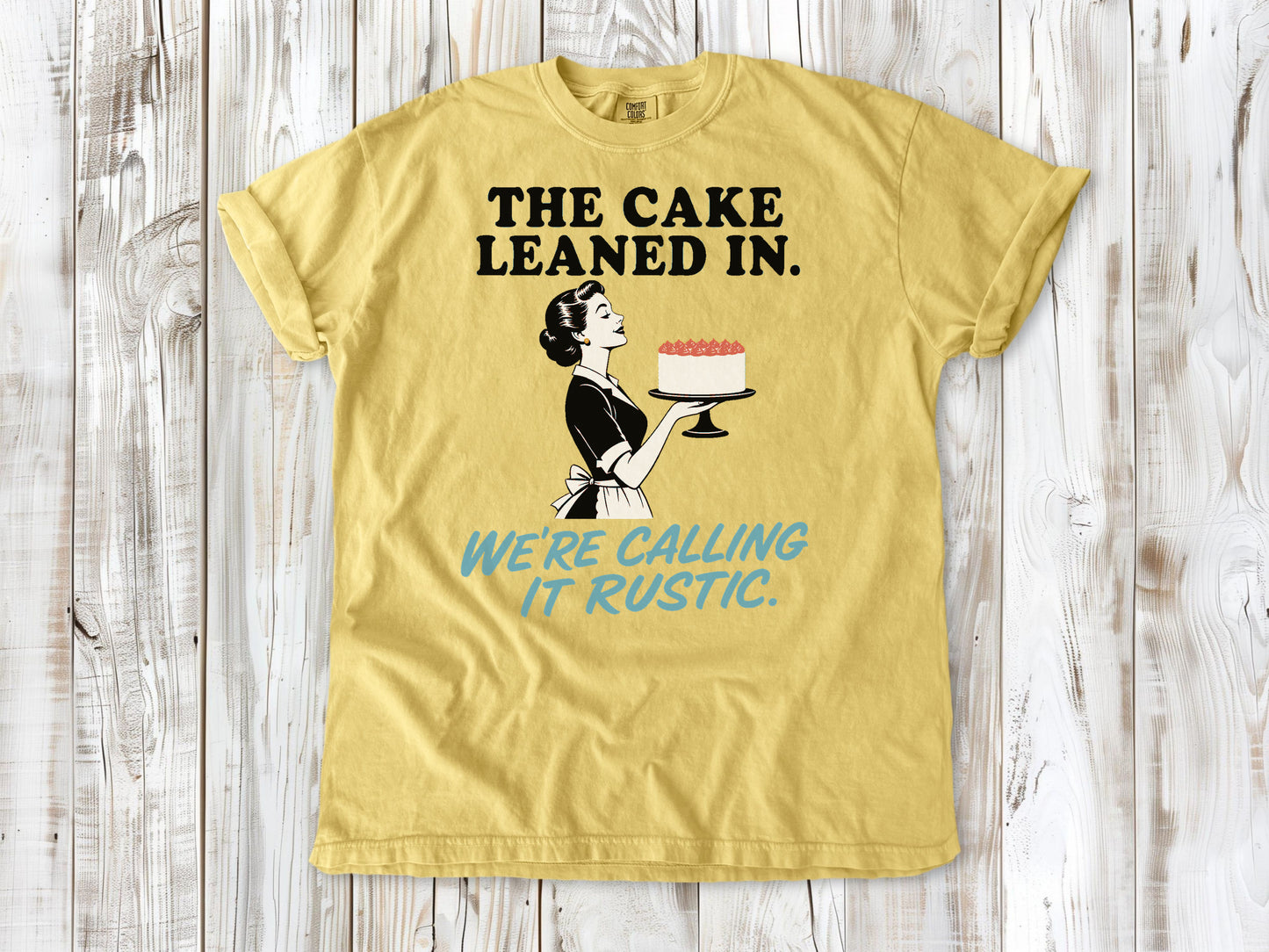 Grey garment-dyed tee with The Cake Leaned In We're Calling It Rustic baking graphic.
