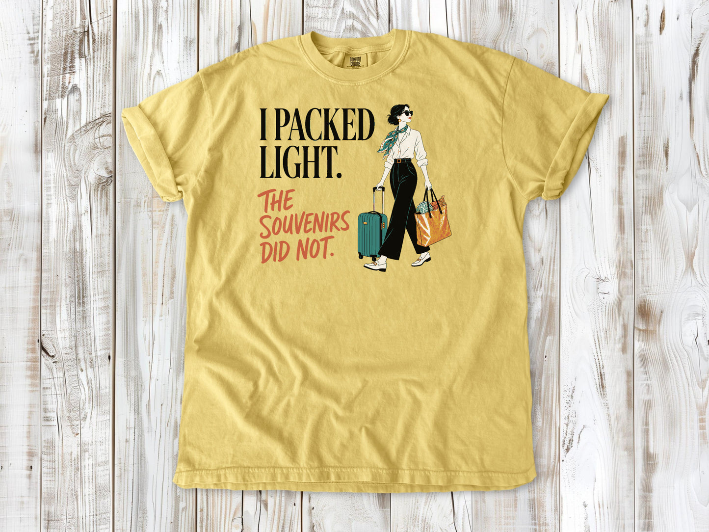 Grey garment-dyed tee with I Packed Light The Souvenirs Did Not travel graphic.