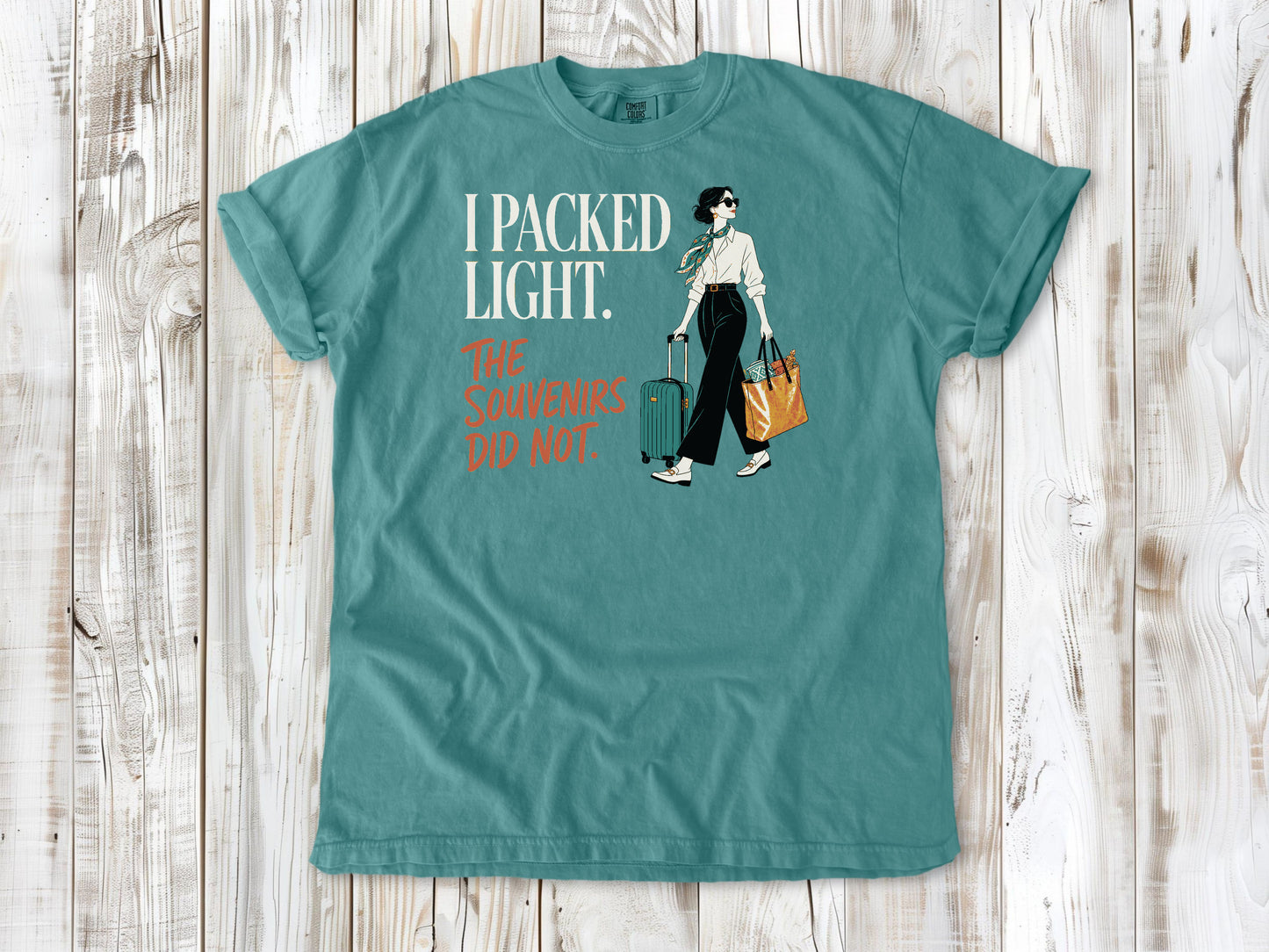 Mustard garment-dyed tee with I Packed Light The Souvenirs Did Not travel graphic.