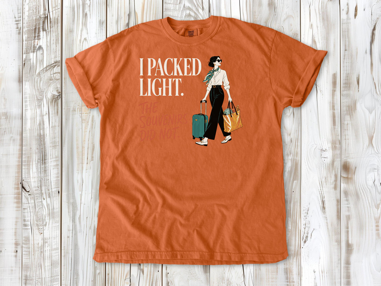 Seafoam garment-dyed tee with I Packed Light The Souvenirs Did Not travel graphic.