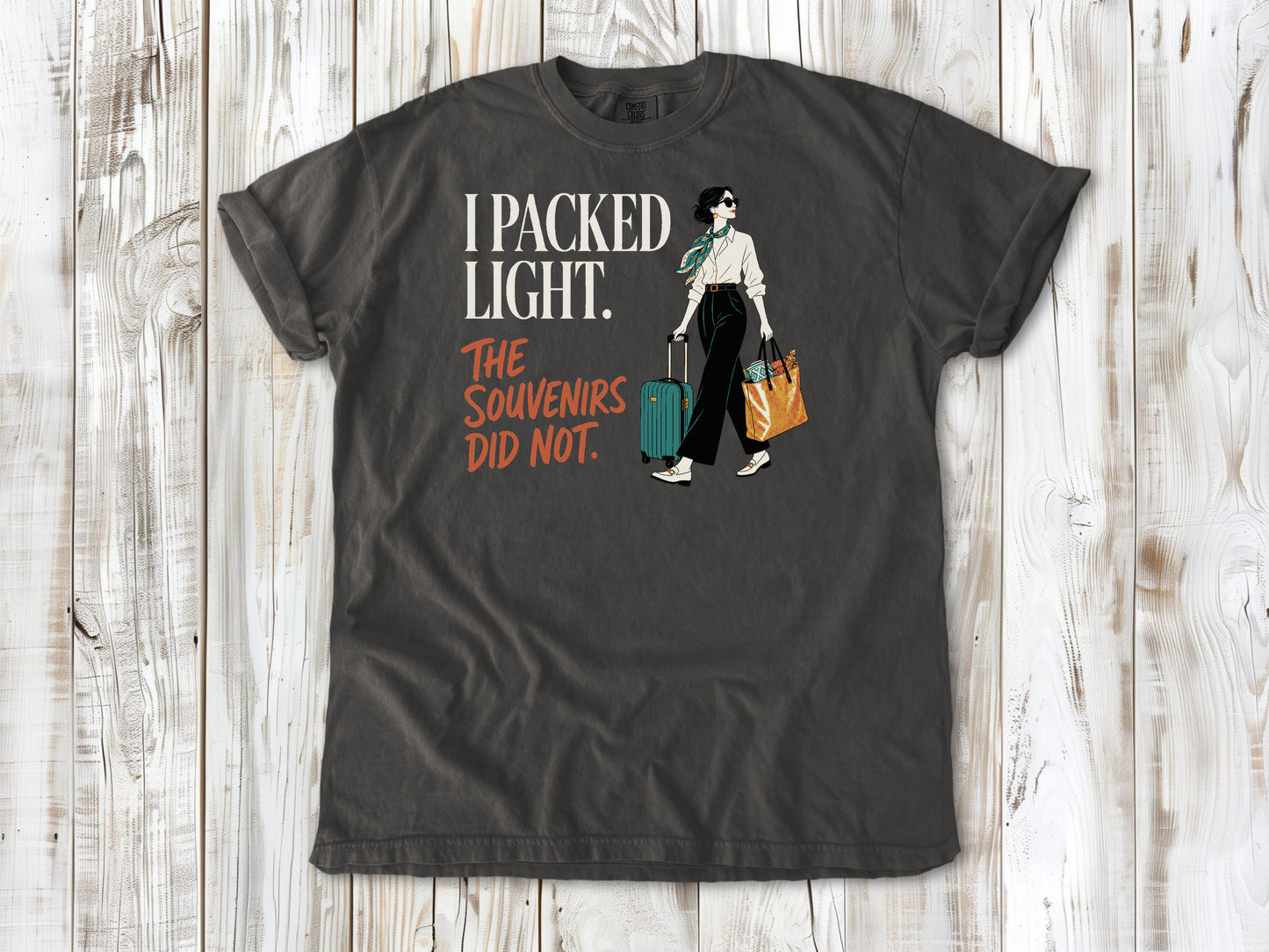 Ivory garment-dyed tee with I Packed Light The Souvenirs Did Not travel graphic.