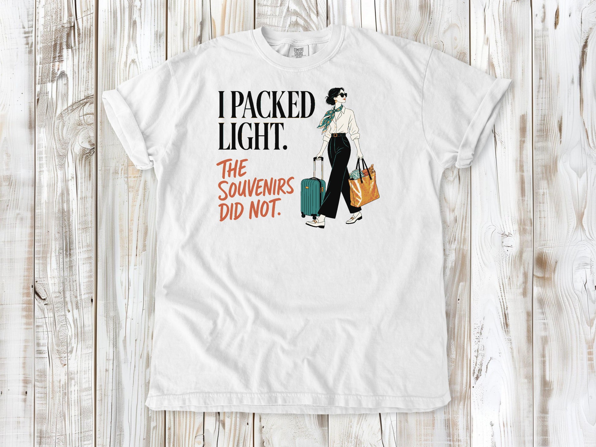 White garment-dyed tee with I Packed Light The Souvenirs Did Not travel graphic.