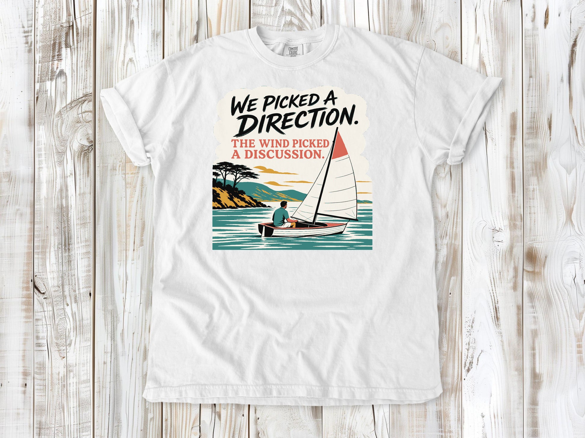 White garment-dyed tee with We Picked a Direction The Wind Picked a Discussion sailing graphic.
