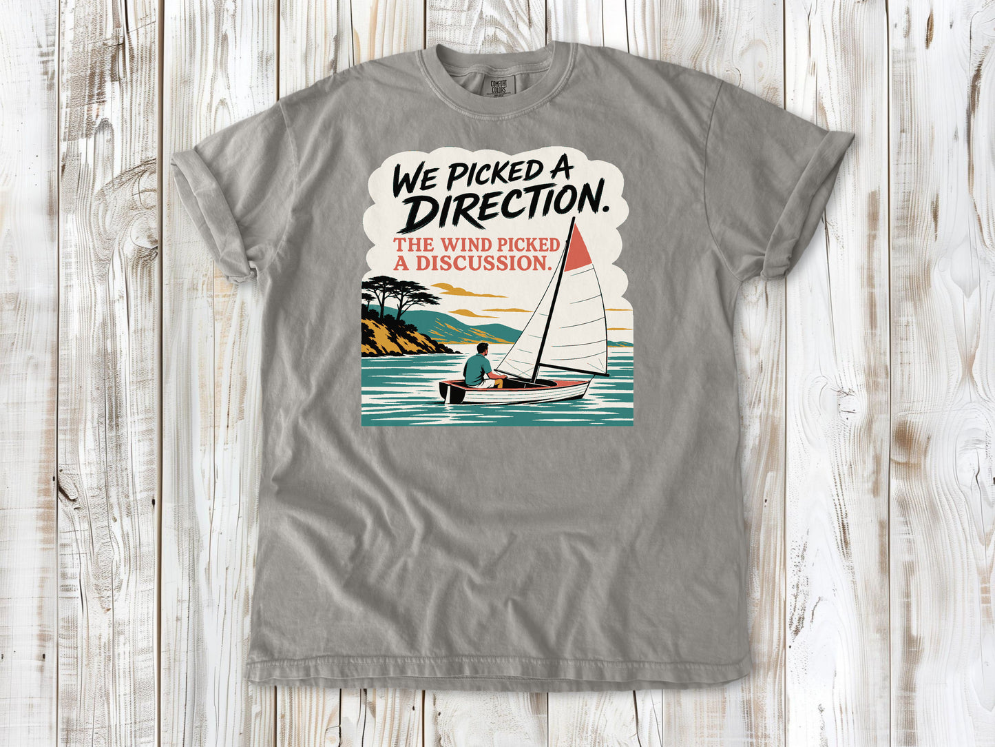 Khaki garment-dyed tee with We Picked a Direction The Wind Picked a Discussion sailing graphic.