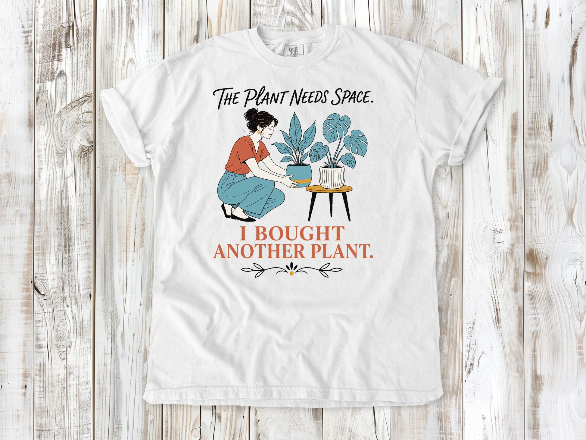 White garment-dyed tee with The Plant Needs Space I Bought Another Plant houseplant graphic.