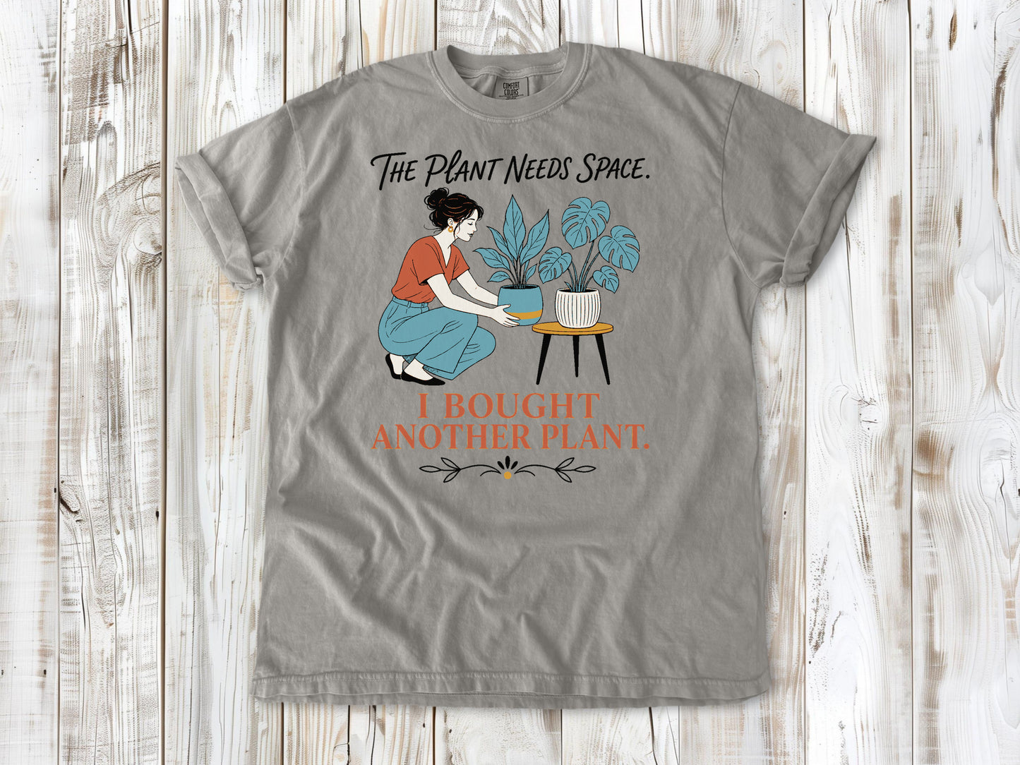 Khaki garment-dyed tee with The Plant Needs Space I Bought Another Plant houseplant graphic.