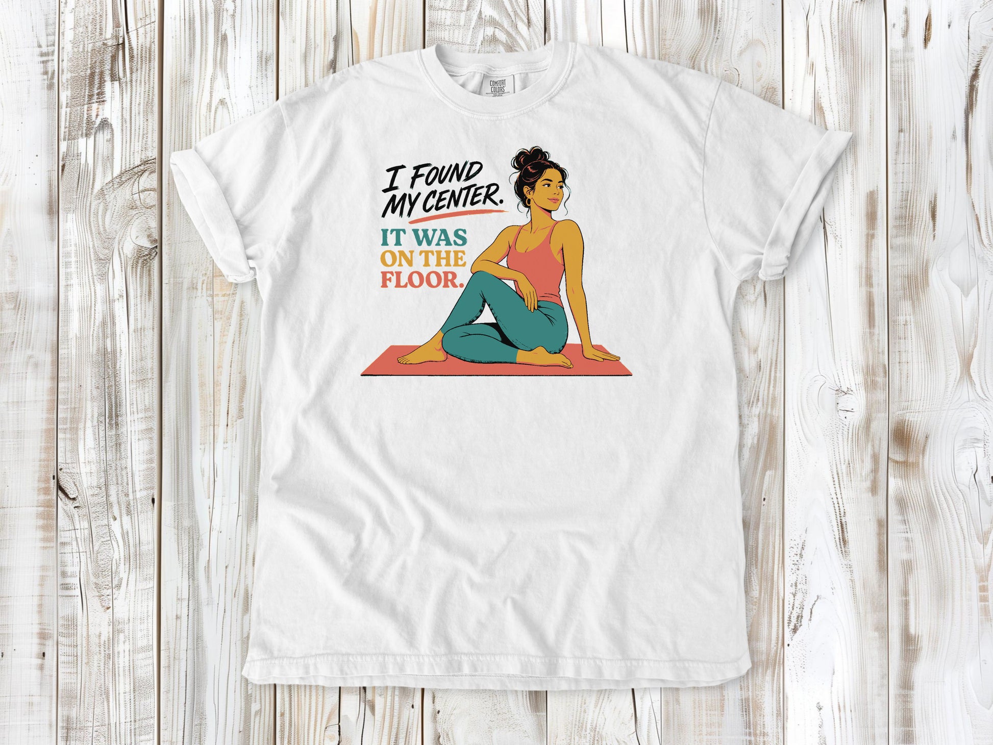 White garment-dyed tee with I Found My Center It Was on the Floor yoga graphic.