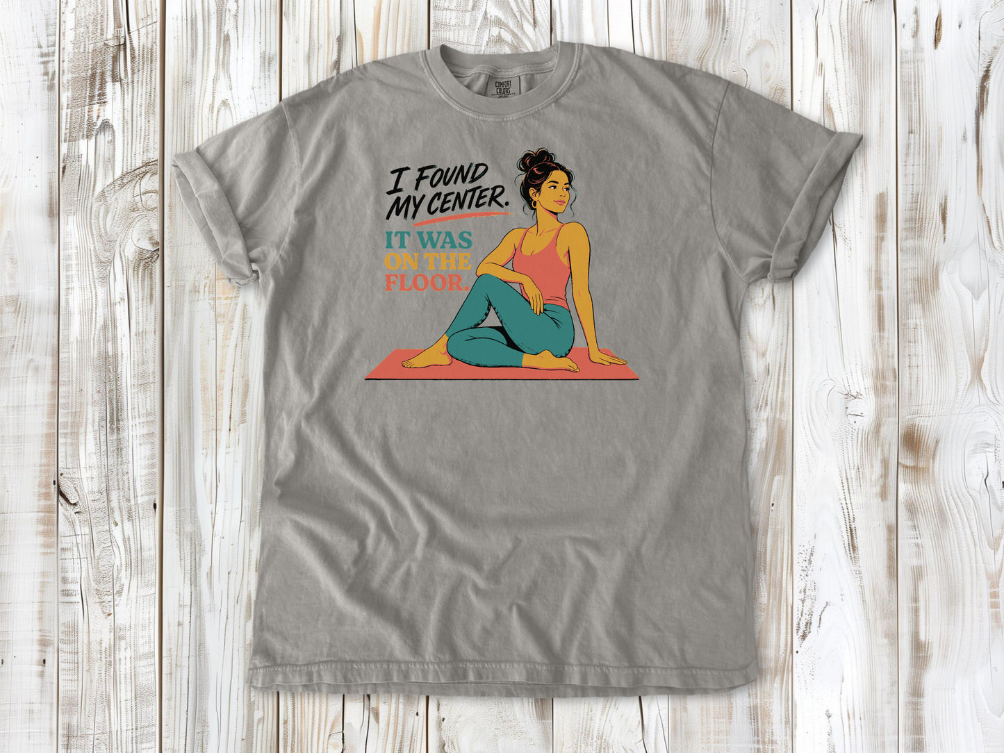 Khaki garment-dyed tee with I Found My Center It Was on the Floor yoga graphic.