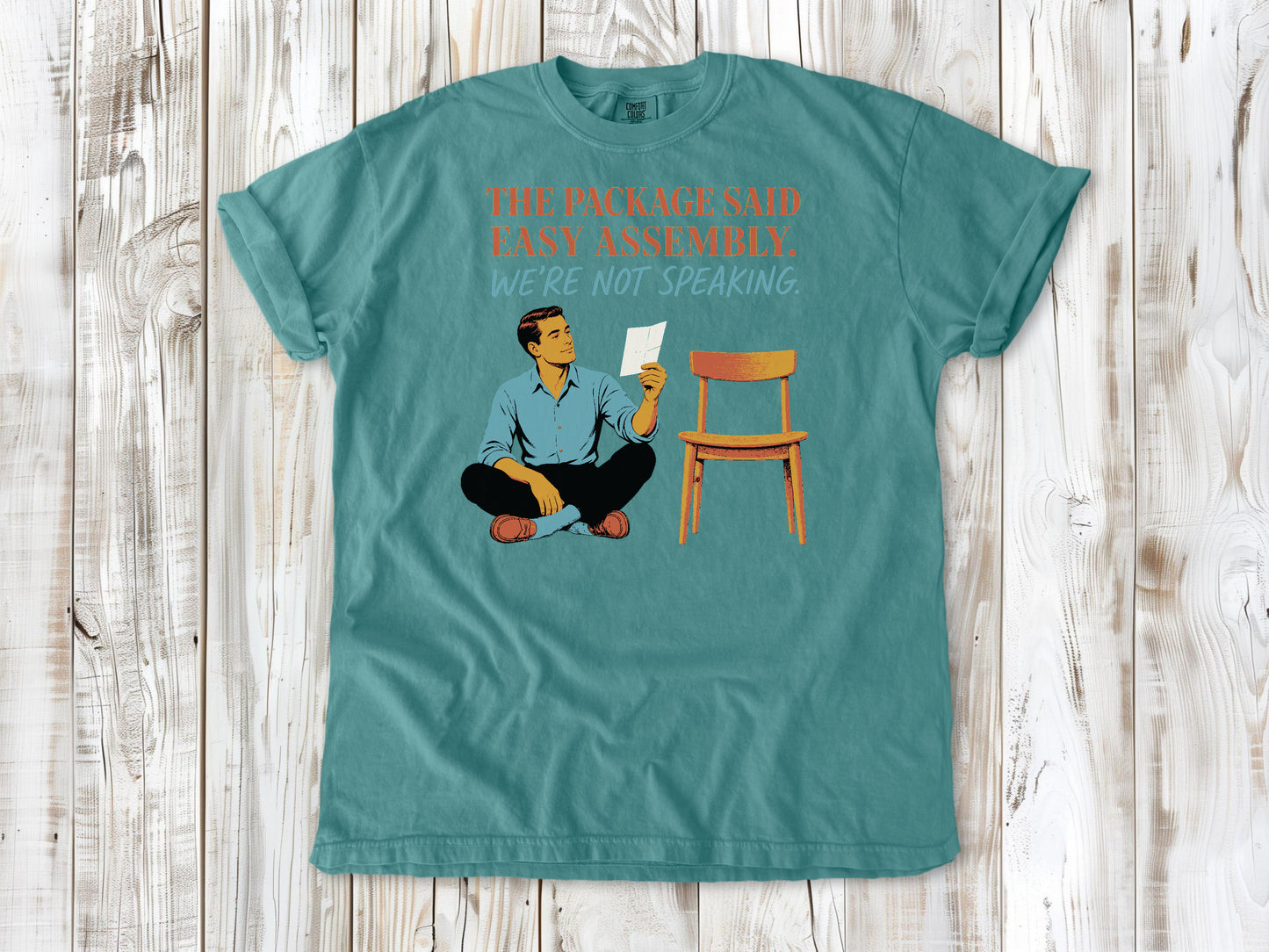 Mustard garment-dyed tee with The Package Said Easy Assembly We're Not Speaking DIY graphic.