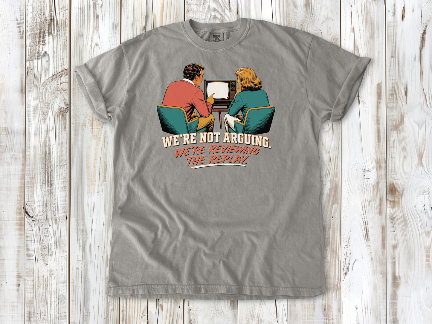 Khaki garment-dyed tee with We're Not Arguing We're Reviewing the Replay game day graphic.
