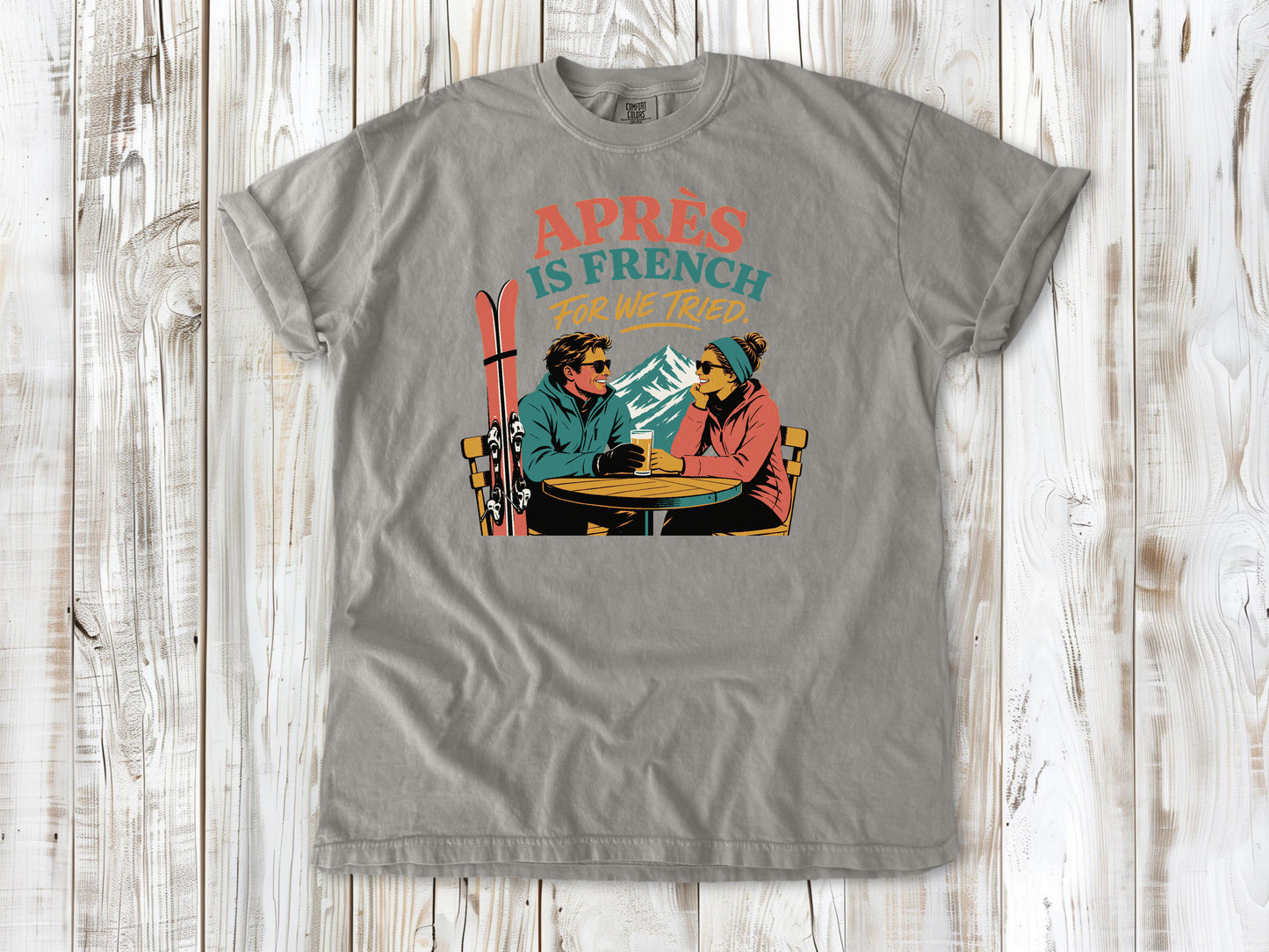 Khaki garment-dyed tee with Après Is French for We Tried skiing graphic.