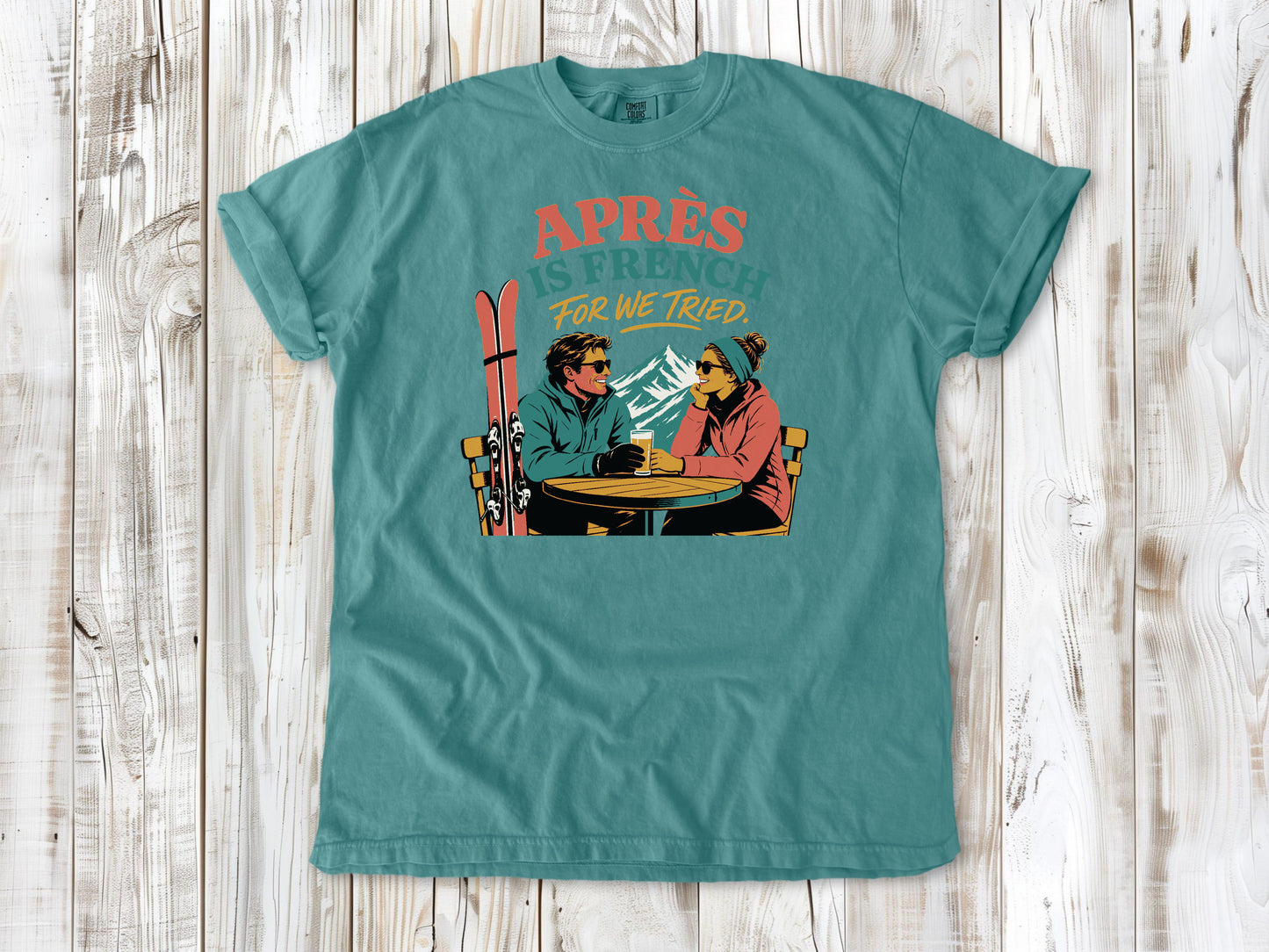 Mustard garment-dyed tee with Après Is French for We Tried skiing graphic.