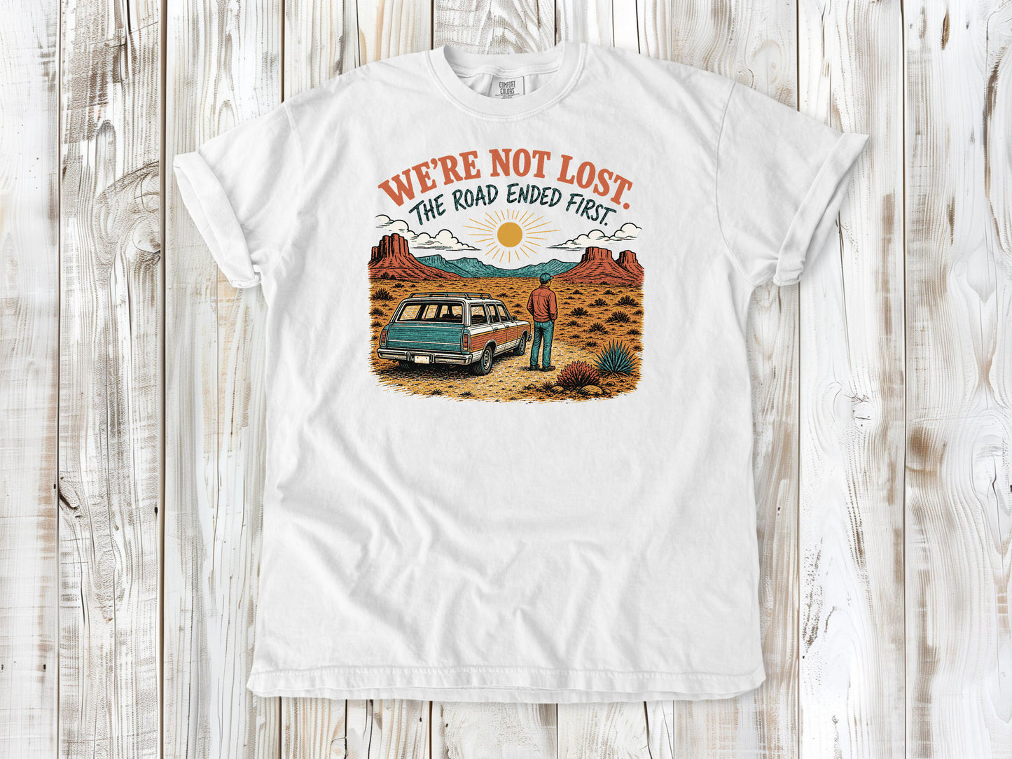 White garment-dyed tee with We're Not Lost The Road Ended First off-road graphic.