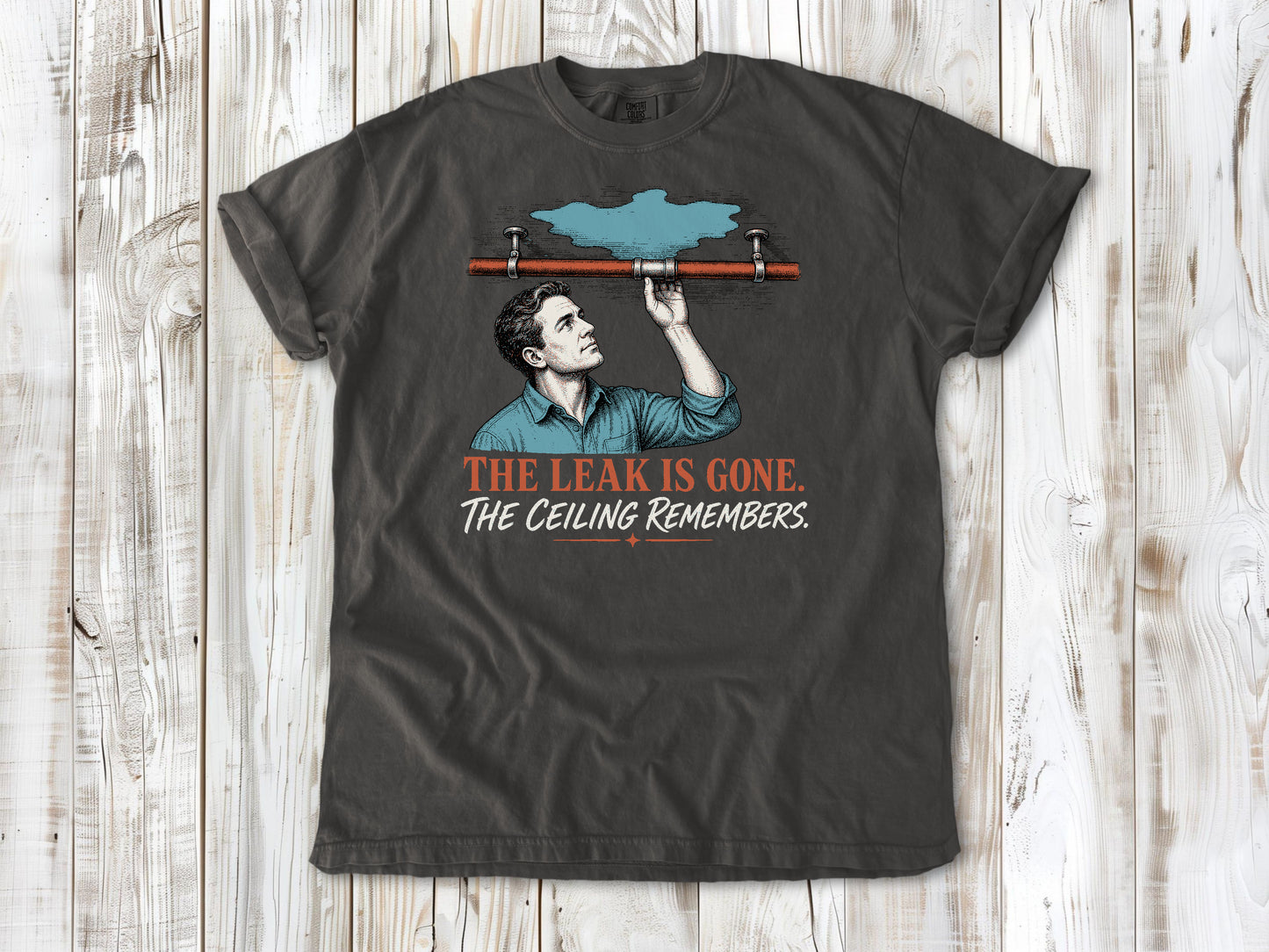 Ivory garment-dyed tee with The Leak Is Gone The Ceiling Remembers home repair graphic.