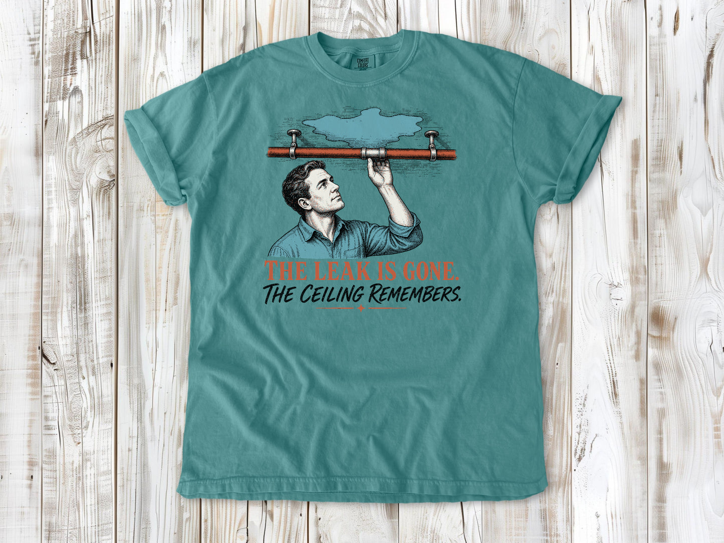 Mustard garment-dyed tee with The Leak Is Gone The Ceiling Remembers home repair graphic.