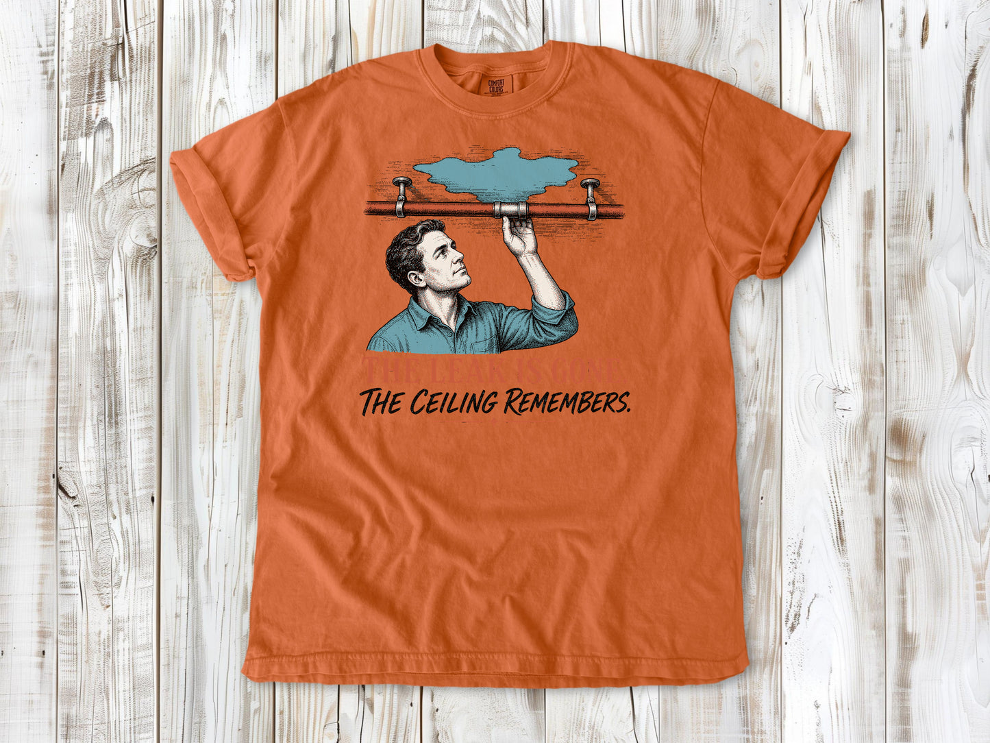 Seafoam garment-dyed tee with The Leak Is Gone The Ceiling Remembers home repair graphic.