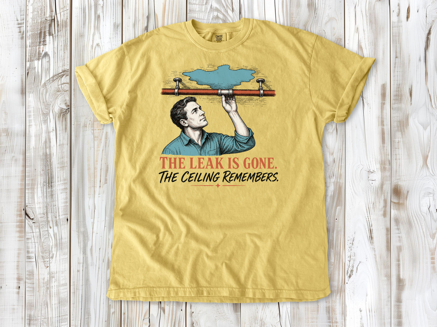 Grey garment-dyed tee with The Leak Is Gone The Ceiling Remembers home repair graphic.