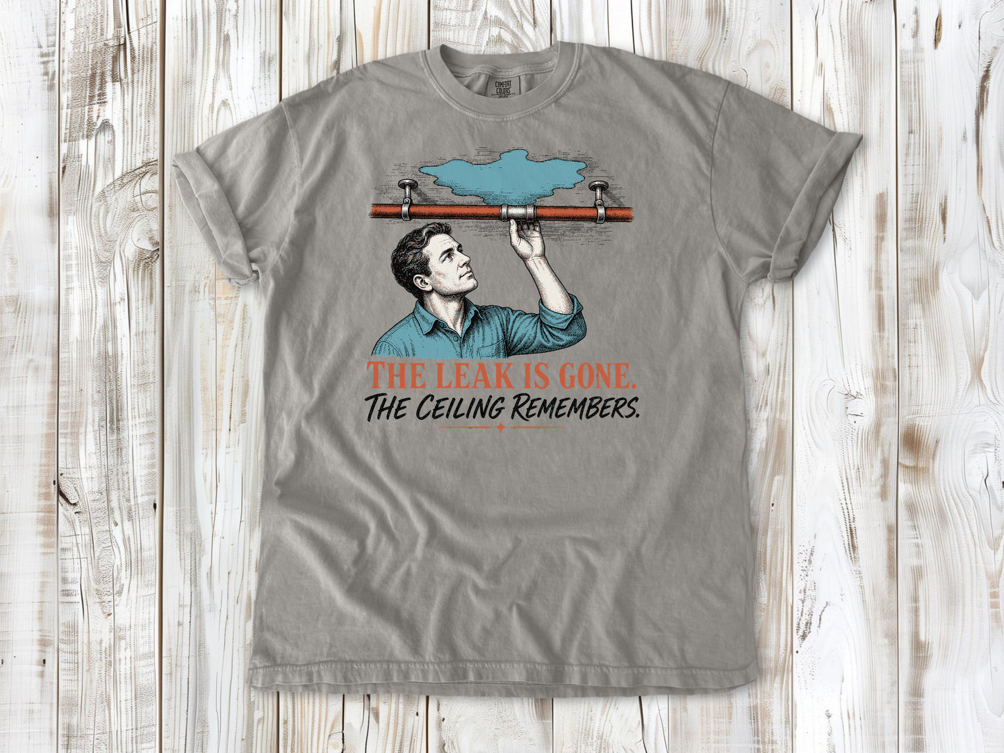 Khaki garment-dyed tee with The Leak Is Gone The Ceiling Remembers home repair graphic.