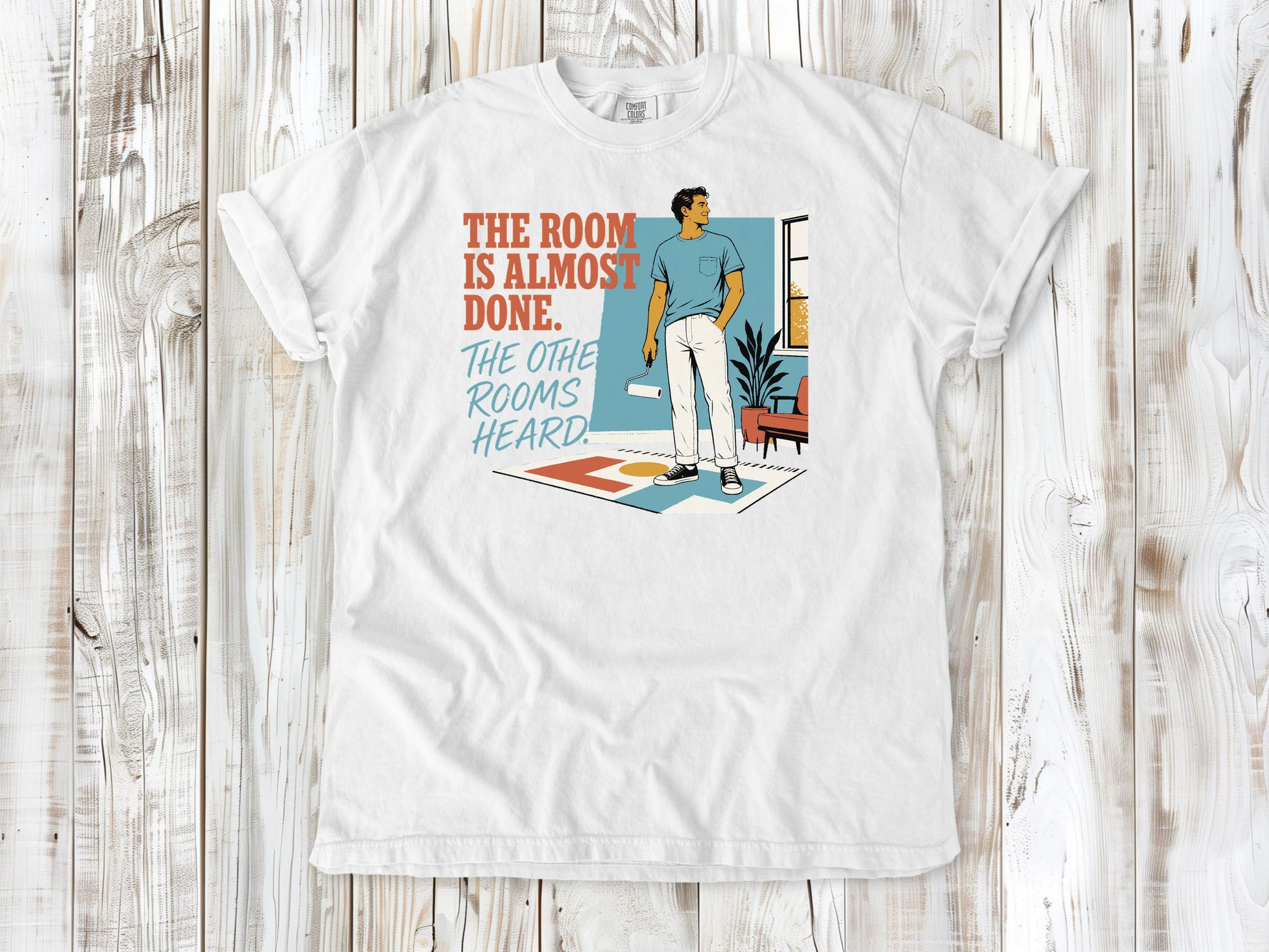 White garment-dyed tee with The Room Is Almost Done The Other Rooms Heard renovation graphic.