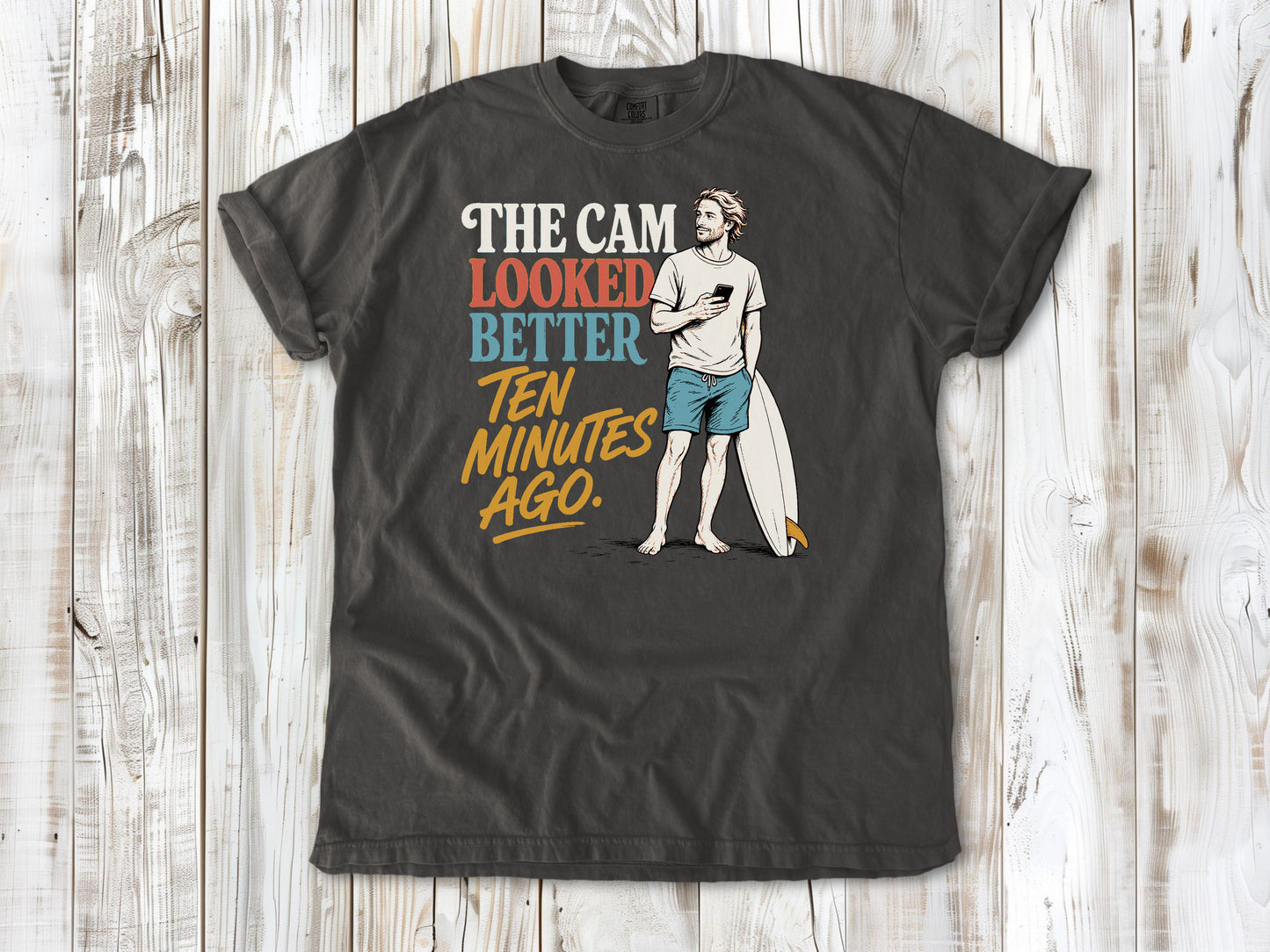 Ivory garment-dyed tee with The Cam Looked Better Ten Minutes Ago surfer graphic.