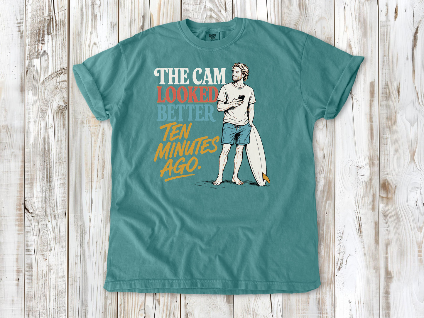 Mustard garment-dyed tee with The Cam Looked Better Ten Minutes Ago surfer graphic.