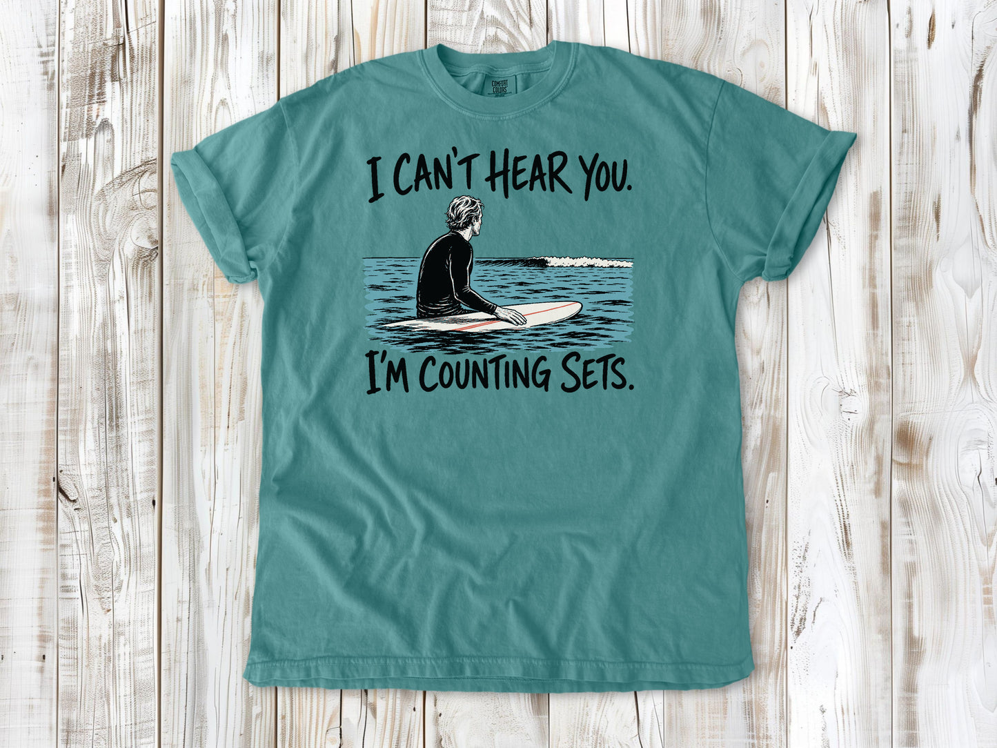 Mustard garment-dyed tee with I Can't Hear You I'm Counting Sets surfer graphic.