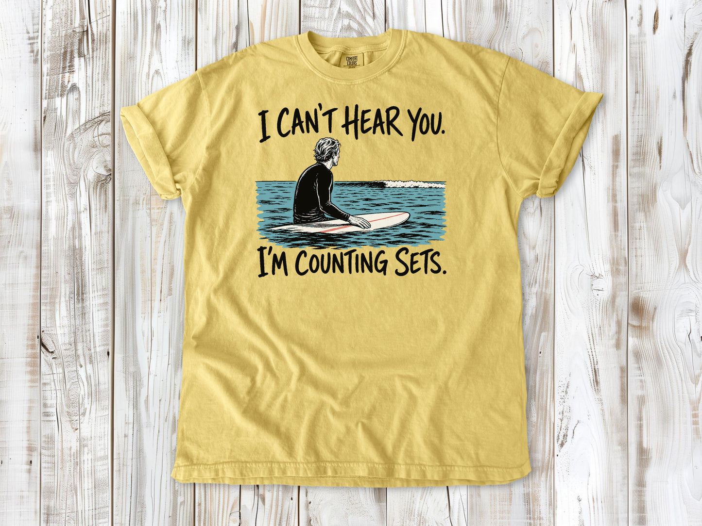 Grey garment-dyed tee with I Can't Hear You I'm Counting Sets surfer graphic.