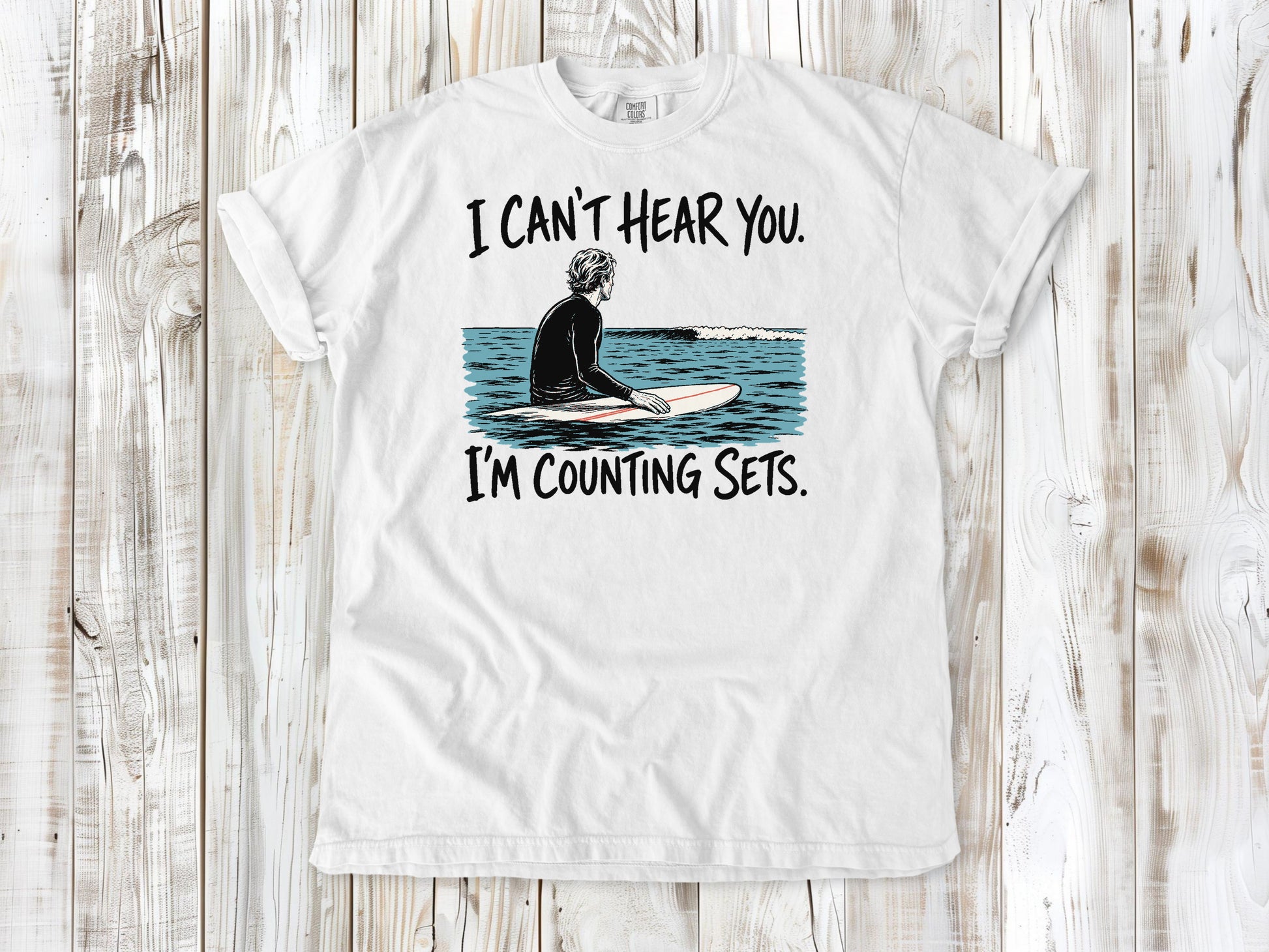 White garment-dyed tee with I Can't Hear You I'm Counting Sets surfer graphic.