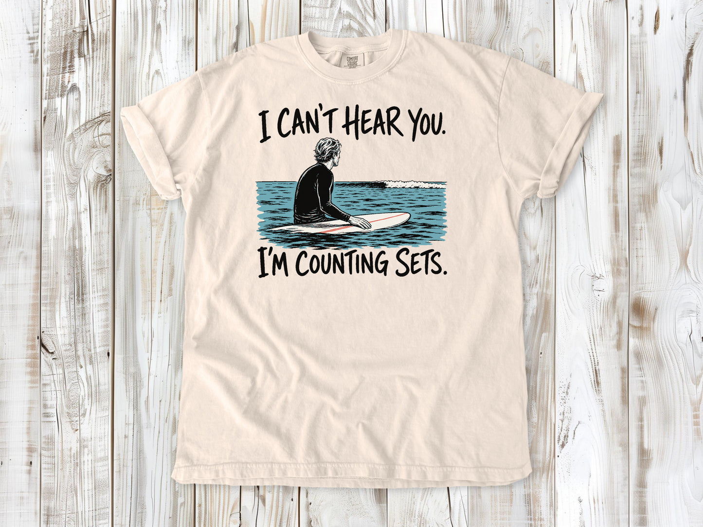 Butter garment-dyed tee with I Can't Hear You I'm Counting Sets surfer graphic.