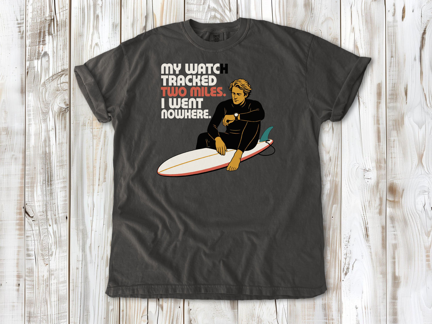 Ivory garment-dyed tee with My Watch Tracked Two Miles I Went Nowhere surfer graphic.