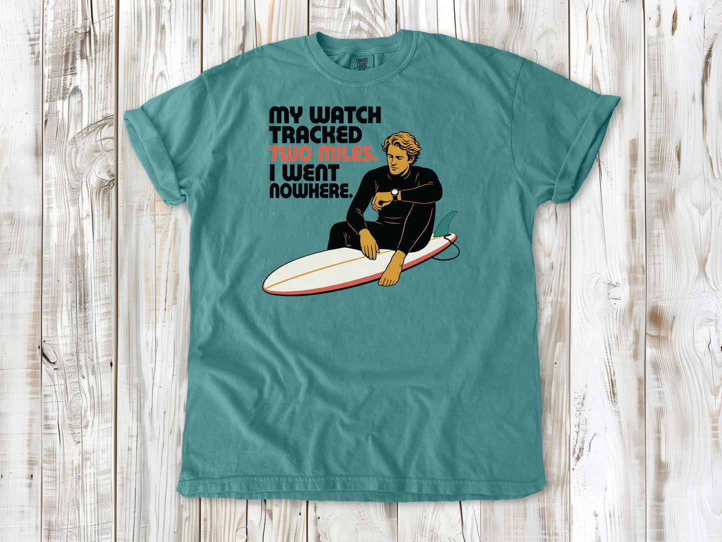 Mustard garment-dyed tee with My Watch Tracked Two Miles I Went Nowhere surfer graphic.