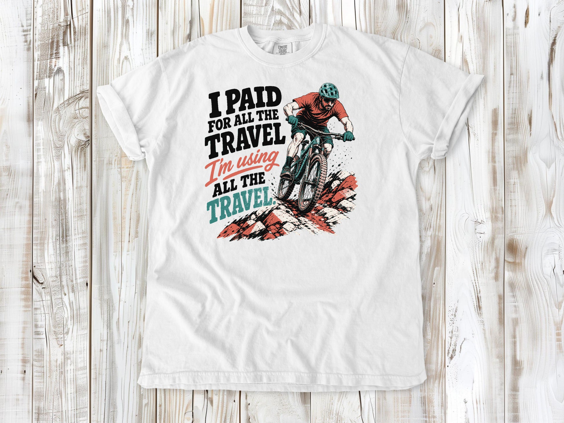 White garment-dyed tee with I Paid for All the Travel mountain bike graphic.