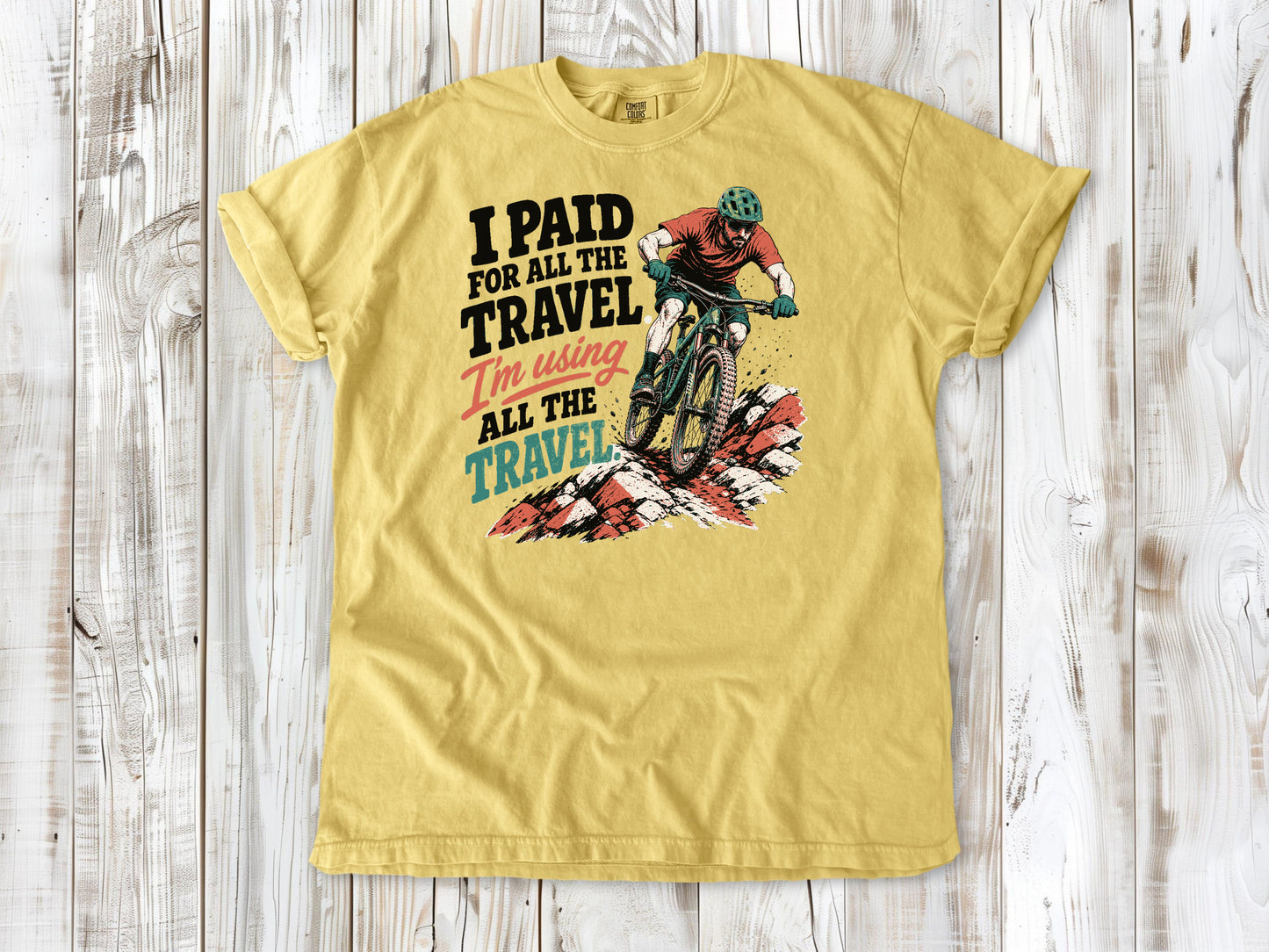 Grey garment-dyed tee with I Paid for All the Travel mountain bike graphic.