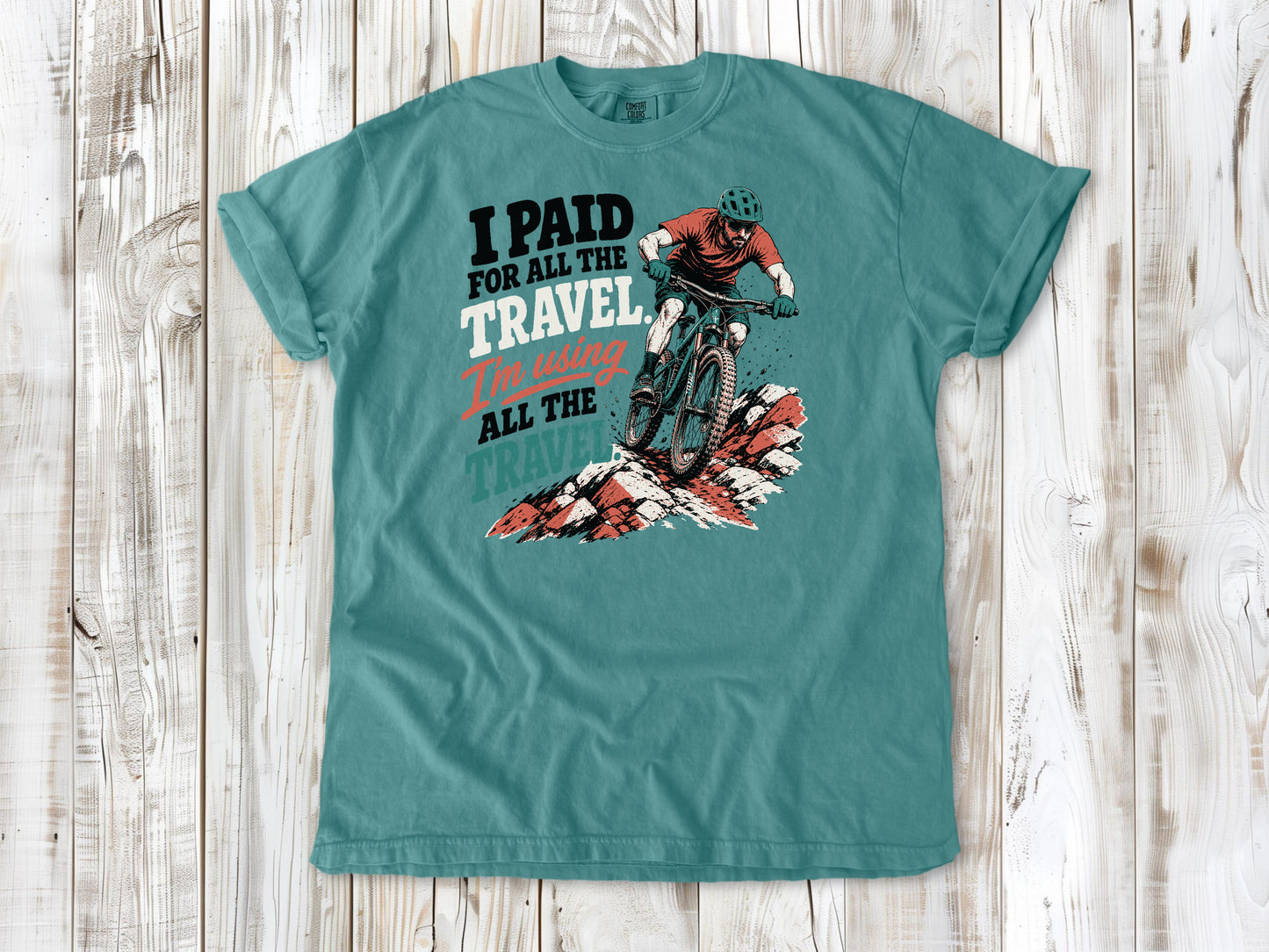 Mustard garment-dyed tee with I Paid for All the Travel mountain bike graphic.