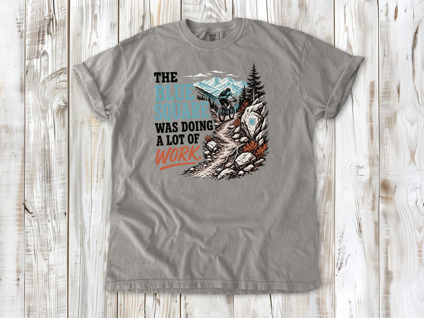 Khaki garment-dyed tee with The Blue Square Was Doing a Lot of Work mountain bike trail graphic.