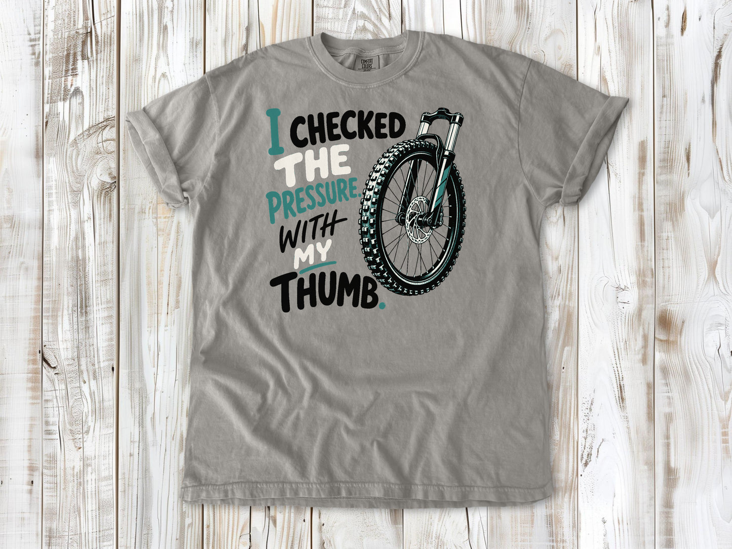 Khaki garment-dyed tee with I Checked the Pressure With My Thumb mountain bike tire graphic.