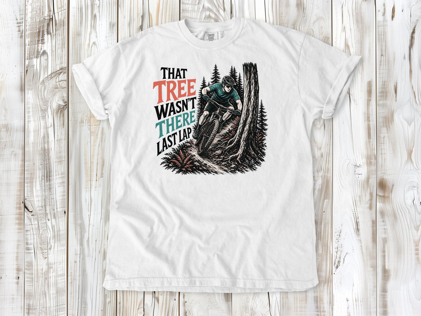 White garment-dyed tee with That Tree Wasn't There Last Lap mountain bike trail graphic.