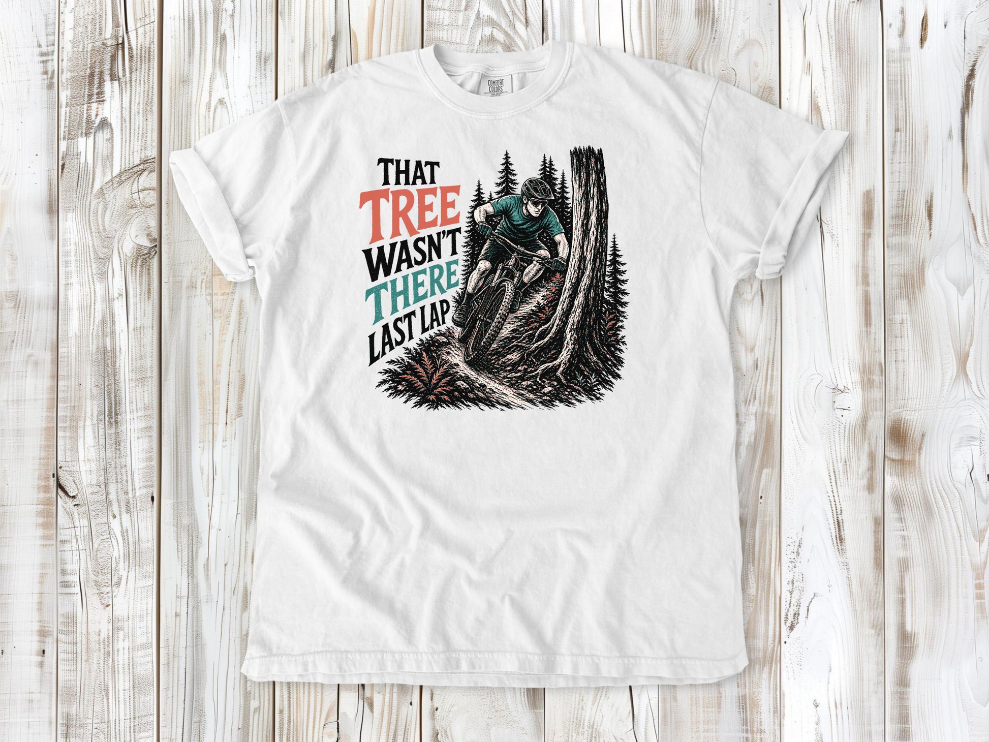 White garment-dyed tee with That Tree Wasn't There Last Lap mountain bike trail graphic.