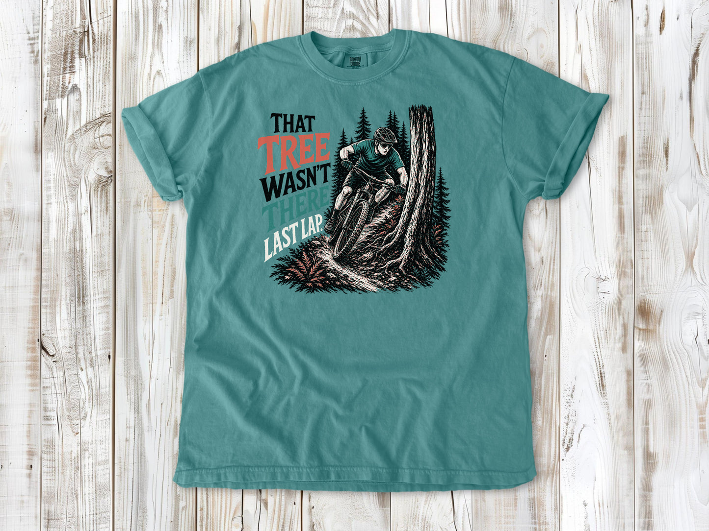 Mustard garment-dyed tee with That Tree Wasn't There Last Lap mountain bike trail graphic.
