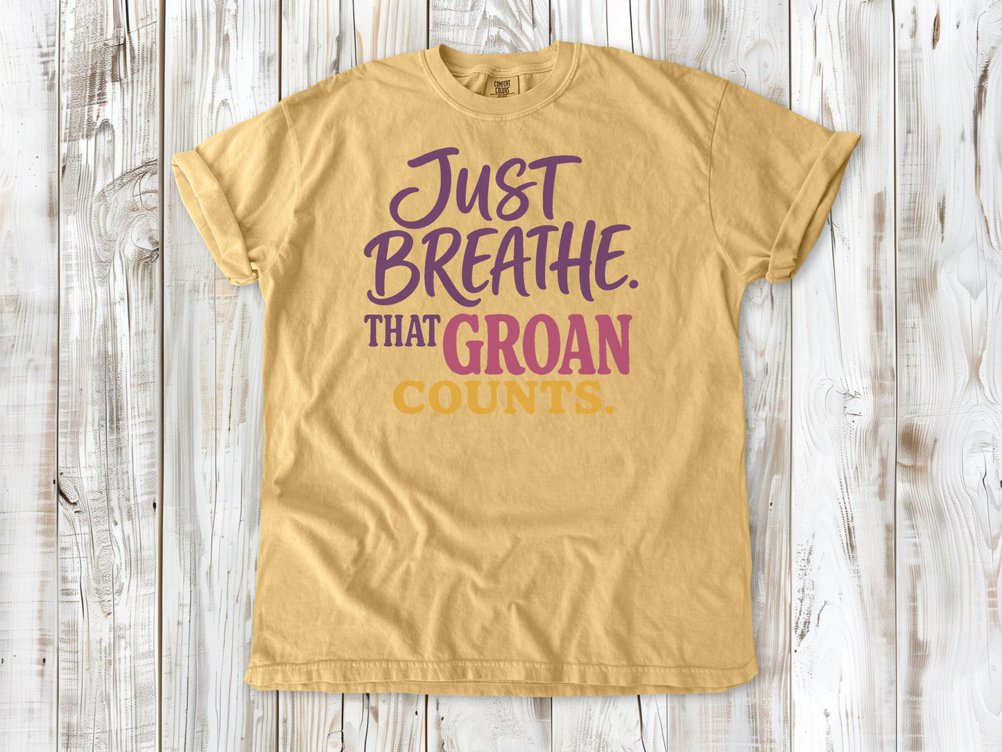 Burnt Orange garment-dyed tee with Just Breathe That Groan Counts yoga graphic.